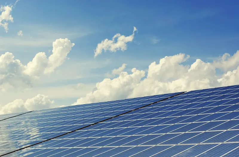 Pannelli fotovoltaici su un tetto, sotto un cielo con nuvole
